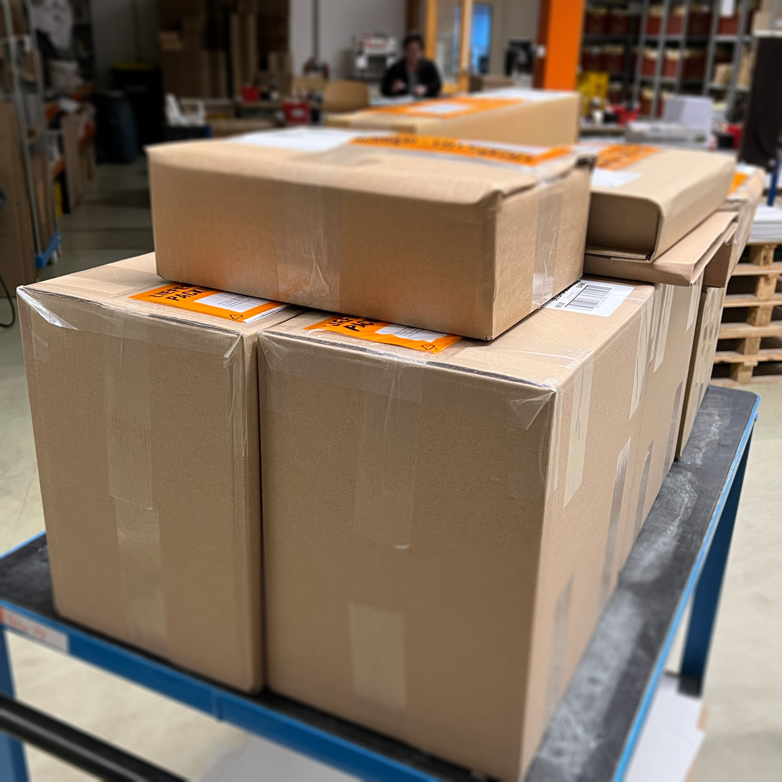 Gestapelte Versandkartons auf einem Transportwagen in der Produktion