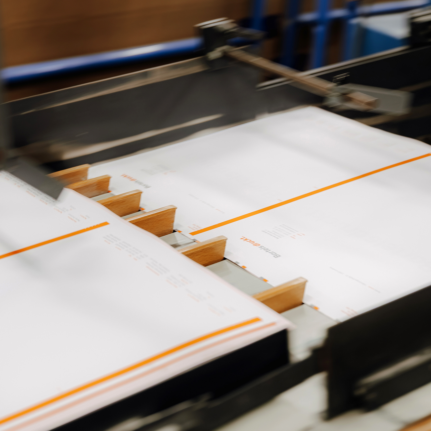 Gedruckte Bögen werden maschinell über eine Förder- und Anschlagmechanik transportiert