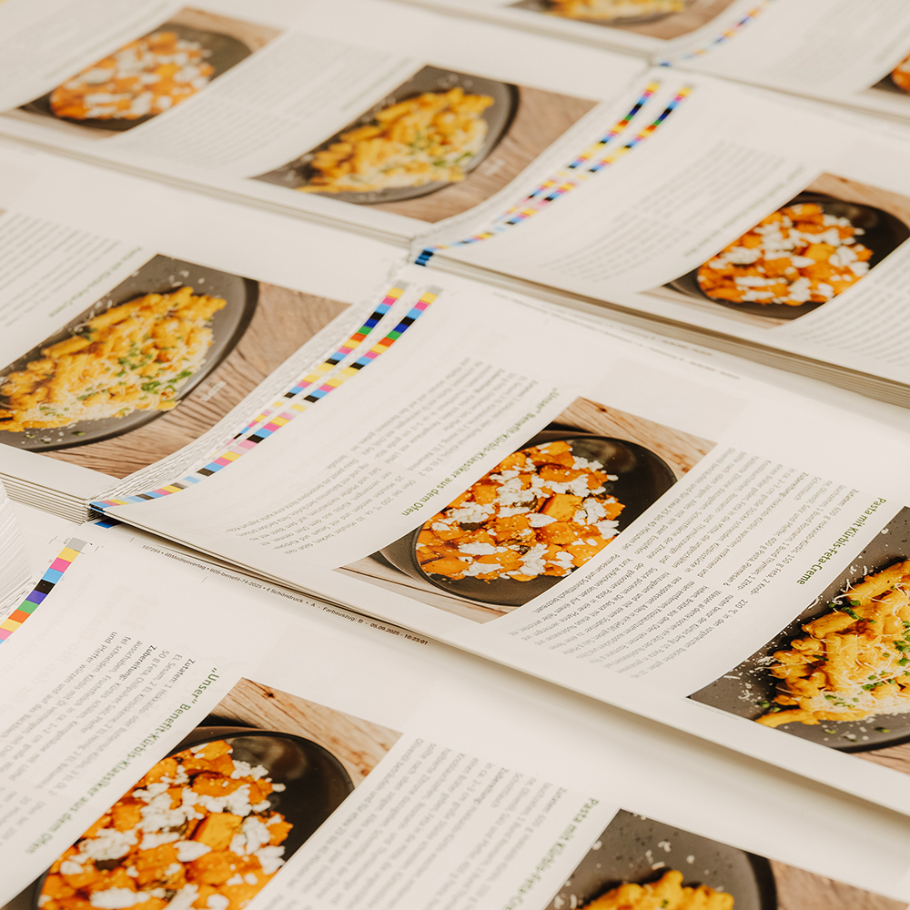 Stapel gedruckter Seiten mit Farbfotos und Text im Druckprozess