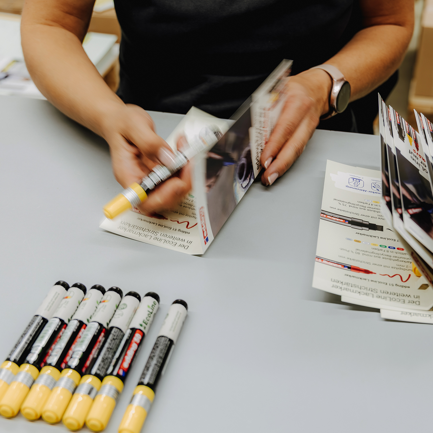 Manuelle Weiterverarbeitung von Flyern durch Falten und Qualitätskontrolle